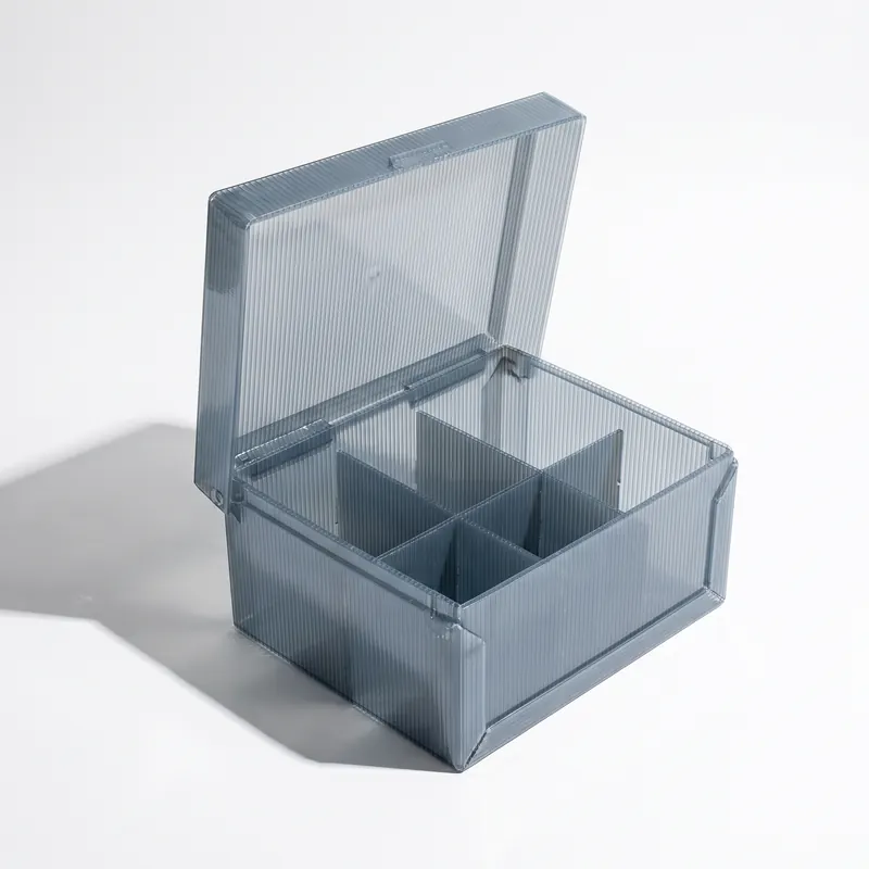 A returnable twin-wall polypropylene box with a hinged lid, open to show a four-cell divider inside.